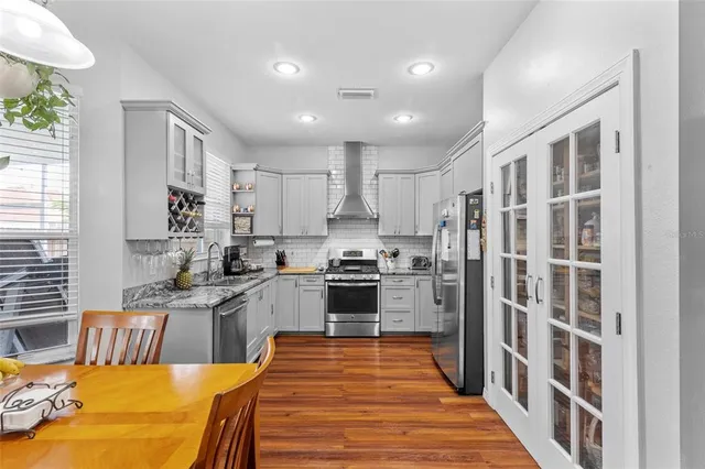 a large kitchen with stainless steel appliances granite countertop a stove a sink dishwasher and a refrigerator with wooden floor