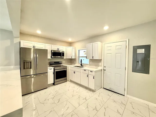 a kitchen with granite countertop a refrigerator and a stove top oven