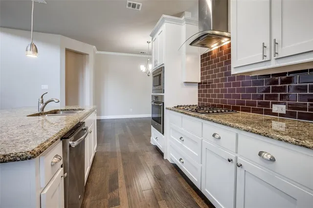 a kitchen with granite countertop a sink stove and cabinets