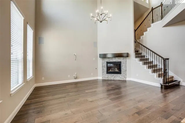 a view of an empty room with wooden floor fireplace and a window