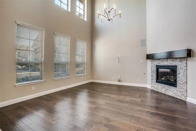 a view of an empty room with wooden floor fireplace and a window
