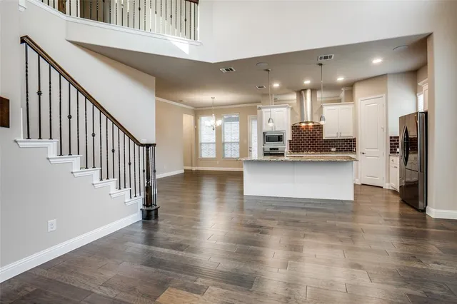 a view of a hallway with wooden floor and a kitchen