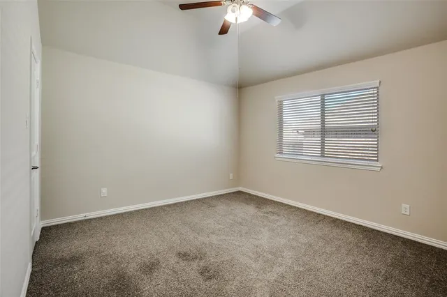 an empty room with a chandelier fan and windows