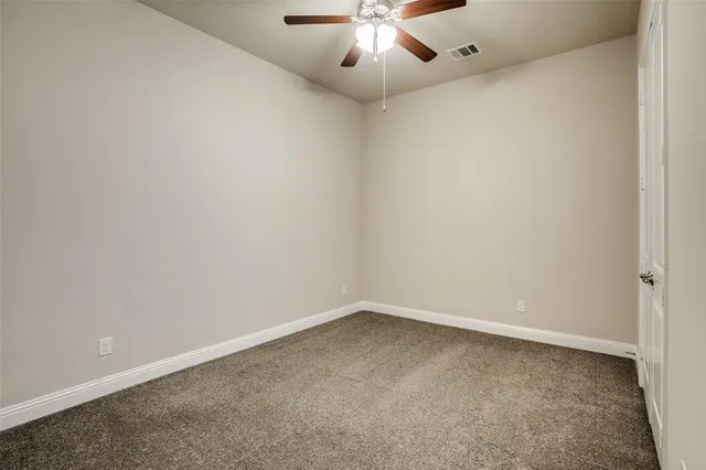 an empty room with a chandelier fan and a window