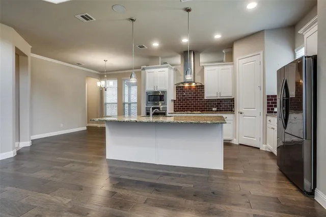 a large kitchen with stainless steel appliances kitchen island a large counter top and wooden floors