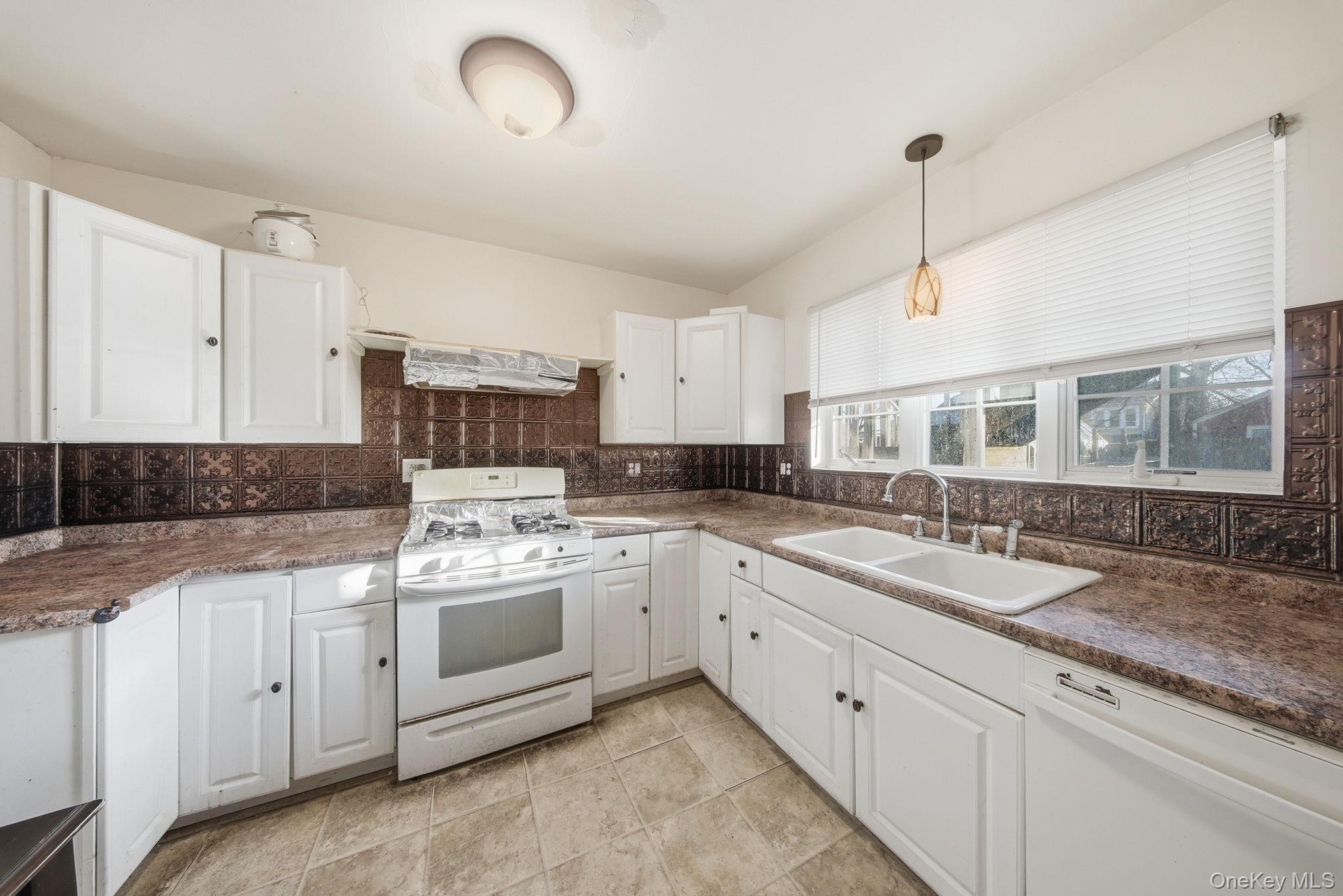 21 Ridge Street Middletown, NY 10940 - Photo 16 of 32 Kitchen featuring white appliances, white cabinets, hanging light fixtures, dark countertops, and decorative backsplash