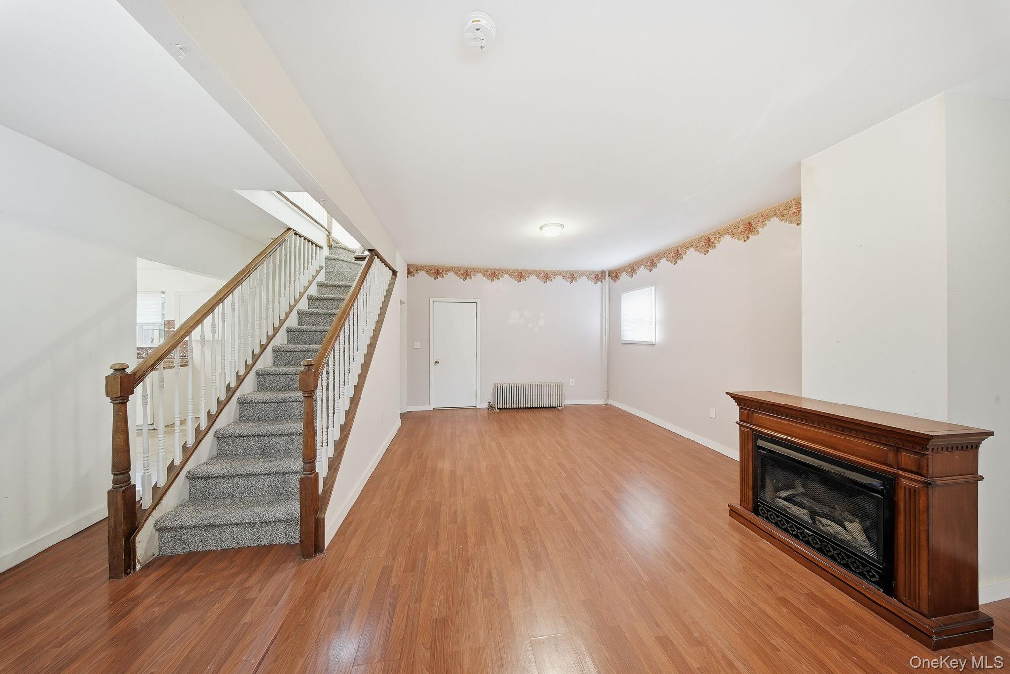 21 Ridge Street Middletown, NY 10940 - Photo 7 of 32 Unfurnished living room featuring stairs, wood finished floors, radiator heating unit