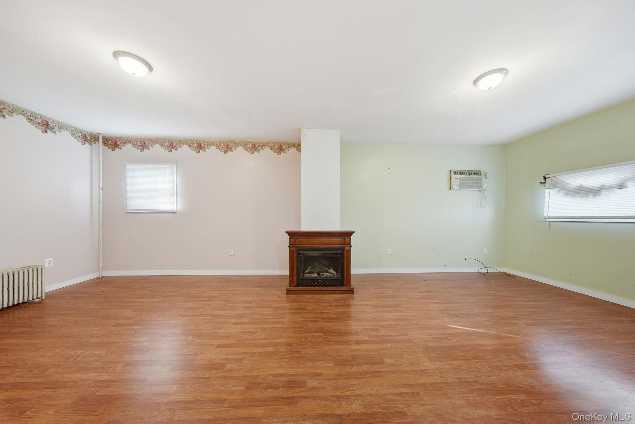 21 Ridge Street Middletown, NY 10940 - Photo 9 of 32 Unfurnished living room featuring plenty of natural light, a fireplace, light wood-style floors, and radiator