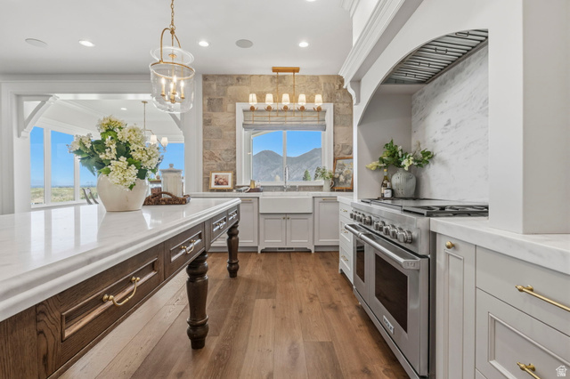 115 East Hidden Ridge Lane, Unit 42 Mapleton, UT 84664 - Photo 11 of 103 Gourmet kitchen featuring a large central island with seating, professional-grade range with custom hood, stone accent wall, and wood-finish flooring