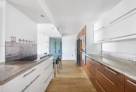 a large white kitchen with granite countertop a sink and a stove