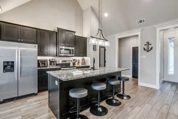 a kitchen with granite countertop stainless steel appliances a sink and a refrigerator