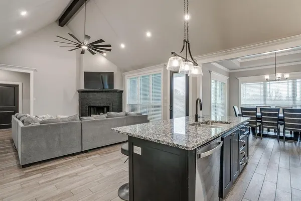 a kitchen with granite countertop a stove a sink a kitchen island with wooden cabinets and granite floor