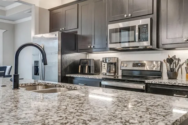 a kitchen with stainless steel appliances granite countertop a stove a microwave and a sink