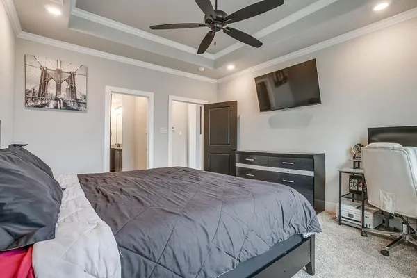 a bedroom with a bed a tv on the wall and dresser
