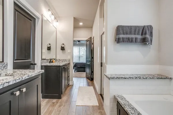 a bathroom with a granite countertop sink a mirror and a bathtub
