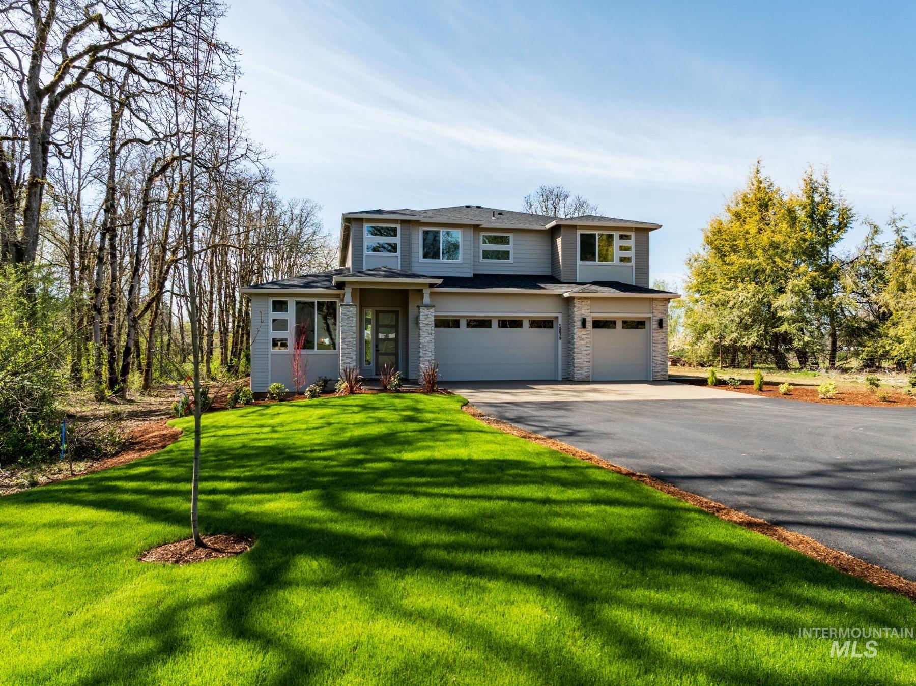 Prairie-style house featuring an attached garage, driveway, a front lawn, and stone siding
