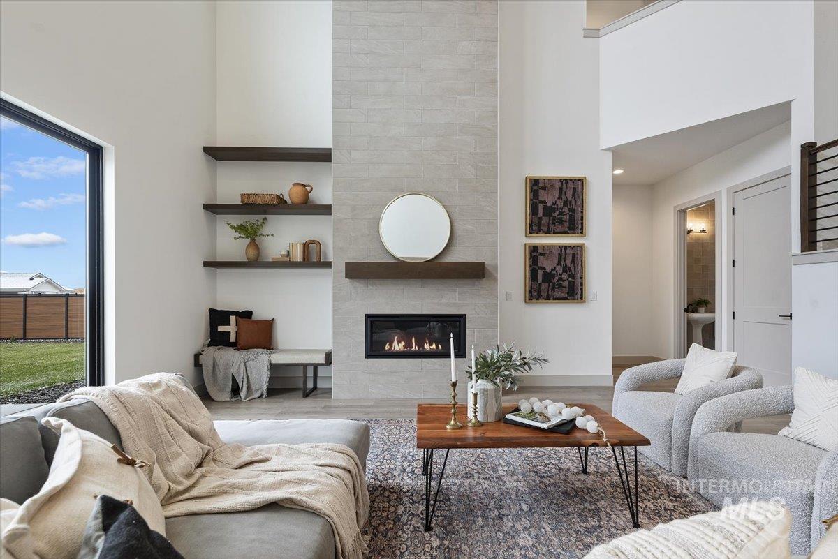 8458 West Graye Street, Unit RAINIER Meridian, ID 83646 - Photo 10 of 29 Living room with a high ceiling, a tiled fireplace, and wood finished floors