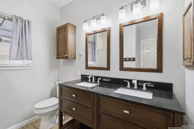a bathroom with a granite countertop toilet sink and mirror
