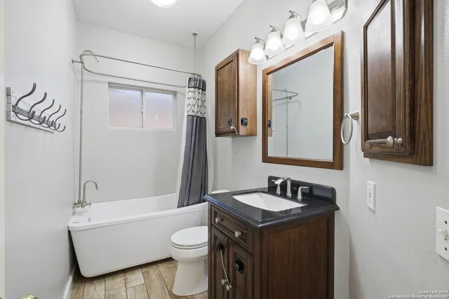 a bathroom with a sink a toilet and shower a mirror