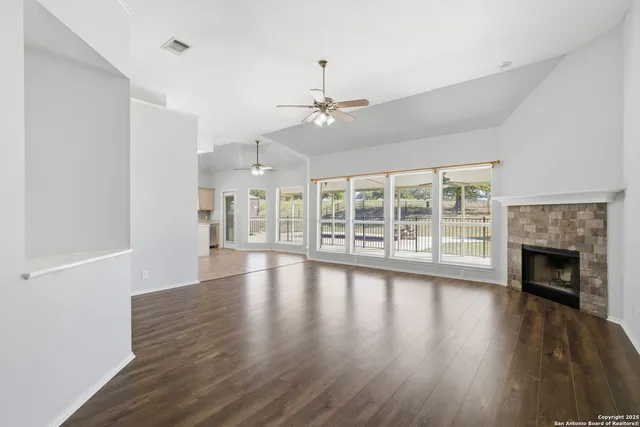 a view of an empty room with wooden floor fireplace and a window