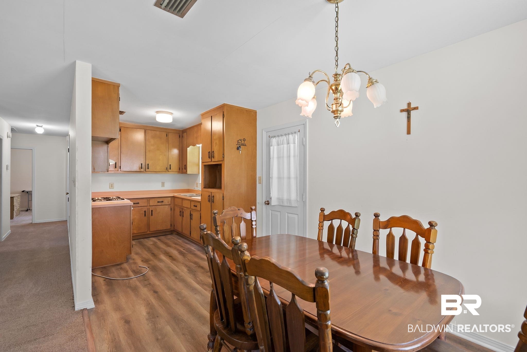 20540 Lacey Road Silverhill, AL 36576 - Photo 9 of 40 Dining area with a brass chandelier, wood-finish flooring, and a kitchen alcove featuring wood cabinetry, a built-in range, and laminate countertops