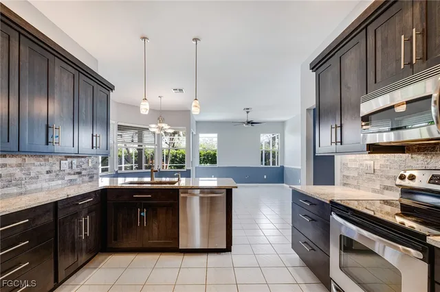 a kitchen with stainless steel appliances granite countertop a sink a stove and a wooden floors