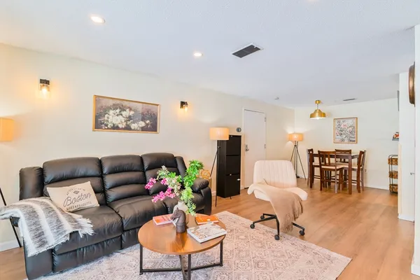 a living room with furniture potted plant and kitchen view