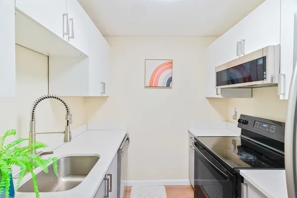 a kitchen with stainless steel appliances a microwave a sink and white cabinets