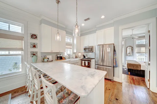 a kitchen with stainless steel appliances granite countertop a refrigerator a oven a sink a stove and white cabinets with wooden floor