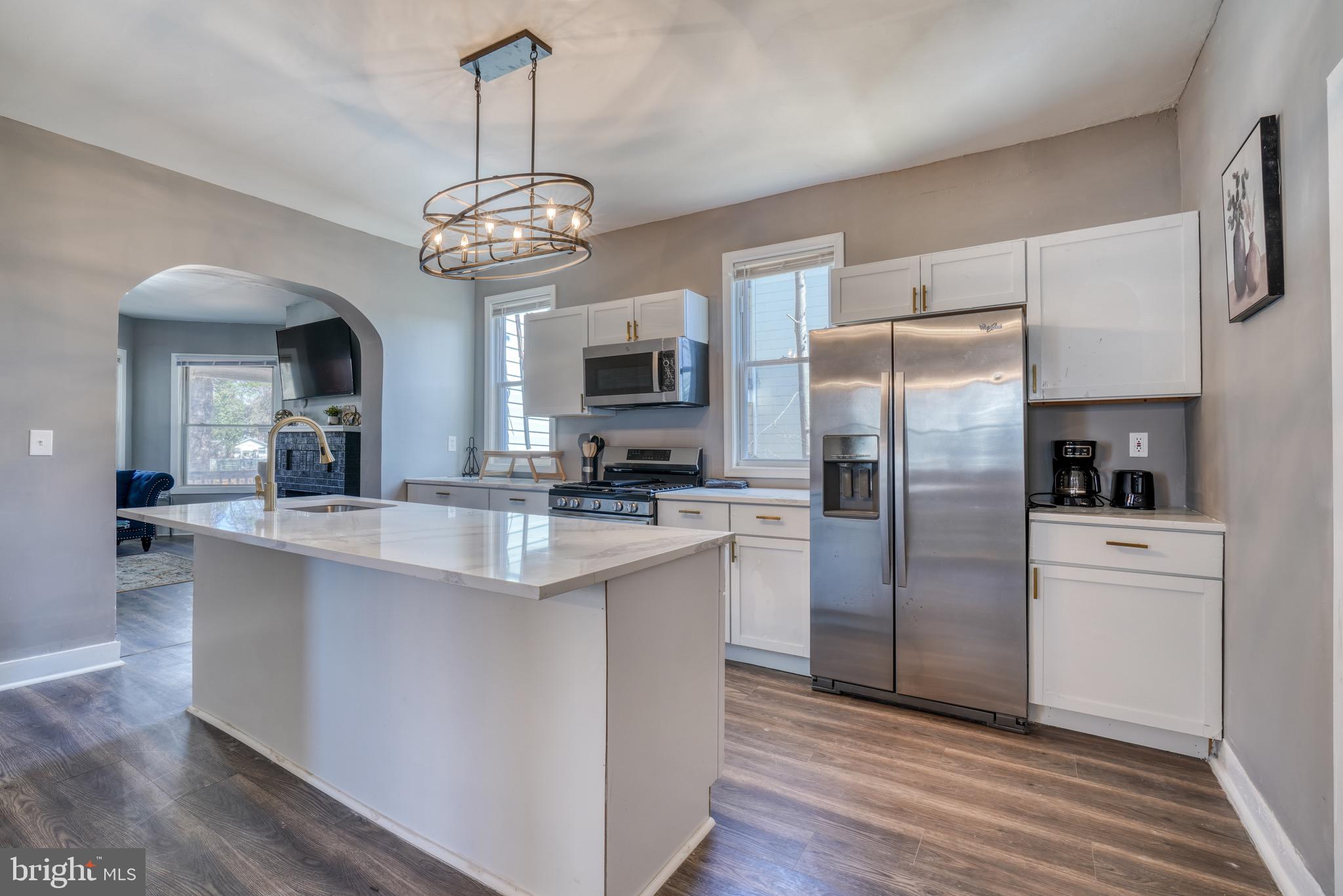 4107 Ridgewood Avenue Baltimore, MD 21215 - Photo 3 of 29 a kitchen with stainless steel appliances a refrigerator a sink dishwasher a oven with white cabinets and wooden floor