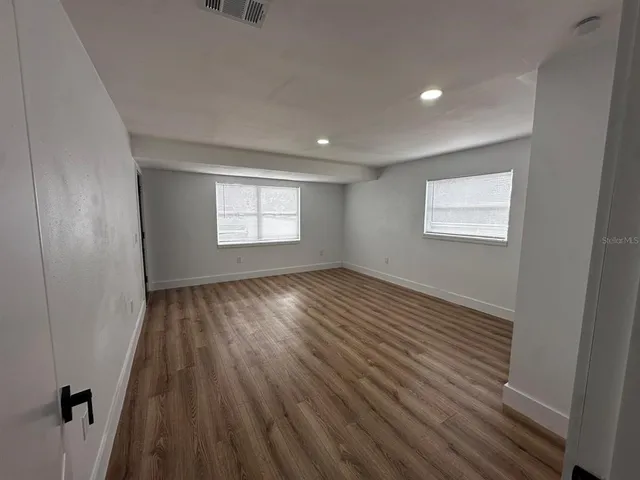 an empty room with wooden floor and windows