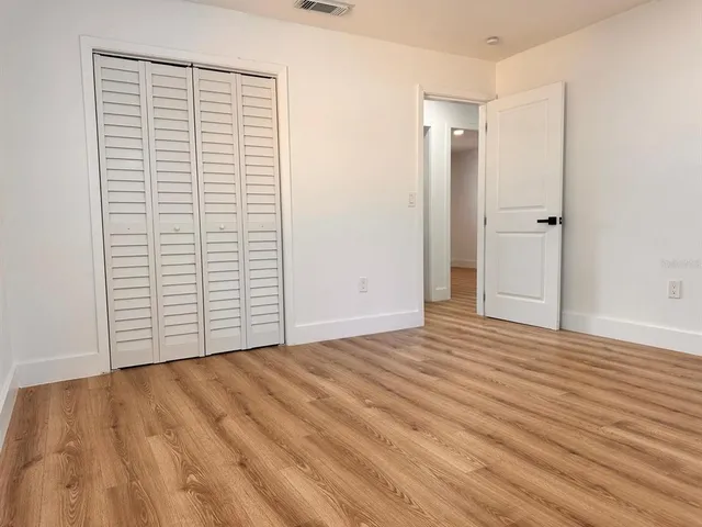 a view of an empty room with closet and a window