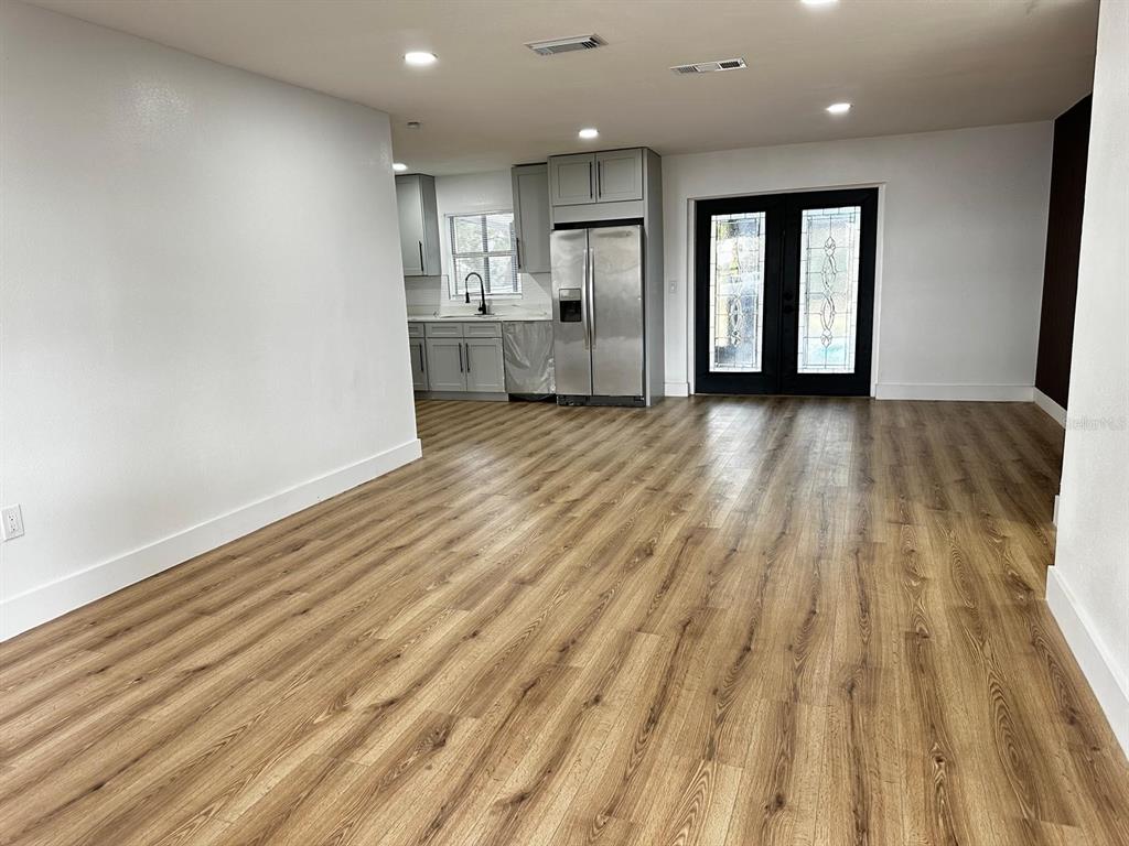 933 Windsor Street Lakeland, FL 33803 - Photo 3 of 47 a view of an empty room and kitchen with wooden floor