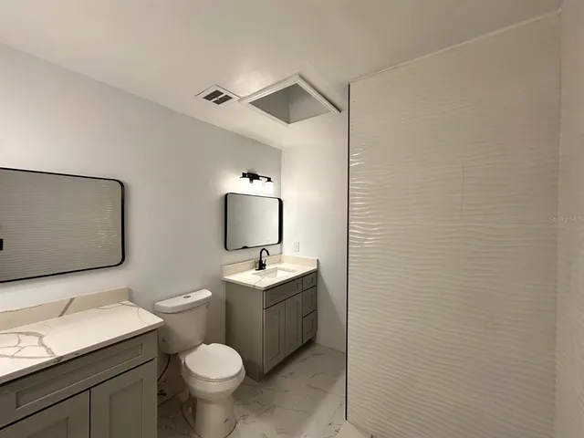 a bathroom with a toilet sink vanity granite and mirror