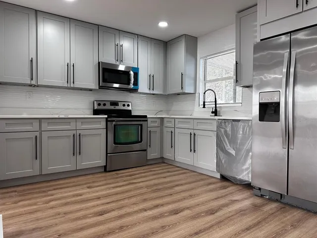 a kitchen with stainless steel appliances granite countertop a stove a sink and a refrigerator