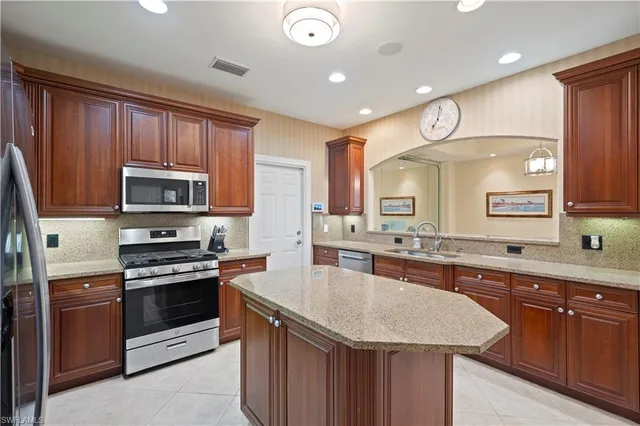 a kitchen with stainless steel appliances granite countertop a stove a sink dishwasher and a microwave oven with wooden floor