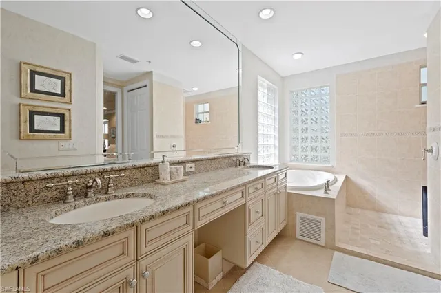 a bathroom with a granite countertop double vanity sink and a bathtub