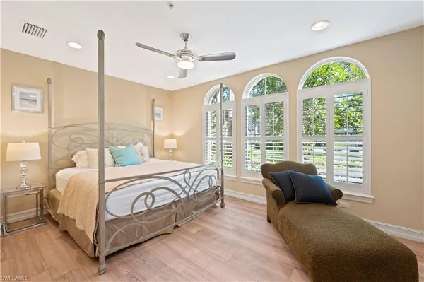 a bedroom with a bed a chandelier and a large window