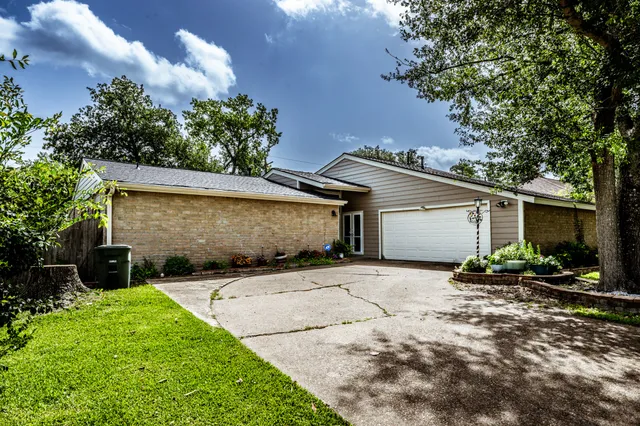 a backyard of a house with table and chairs under an umbrella