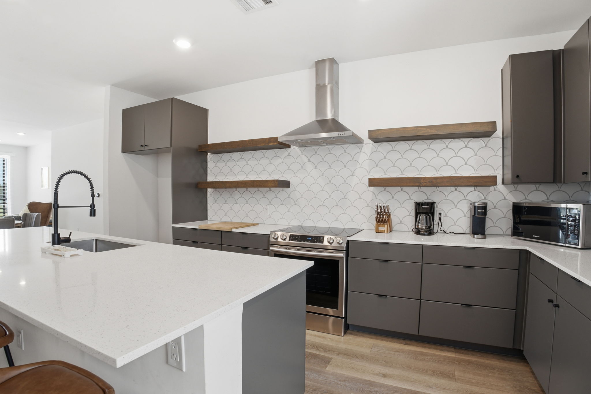 2709 East 5th Street, Unit 1306 Austin, TX 78702 - Photo 2 of 28 A well-appointed kitchen features sleek gray cabinetry and bright white countertops, creating an inviting space for culinary endeavors.
