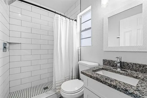 a bathroom with a granite countertop sink a toilet and shower