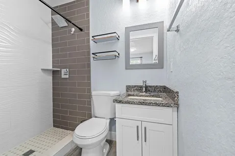 a bathroom with a granite countertop toilet sink and mirror
