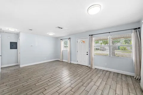 an empty room with wooden floor and windows