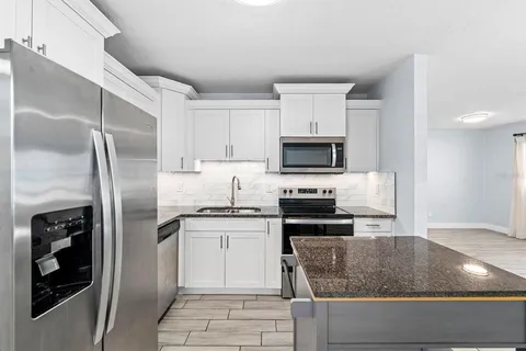 a kitchen with stainless steel appliances granite countertop a refrigerator a stove and a sink