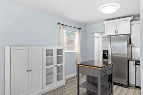 a kitchen with a refrigerator and wooden floor
