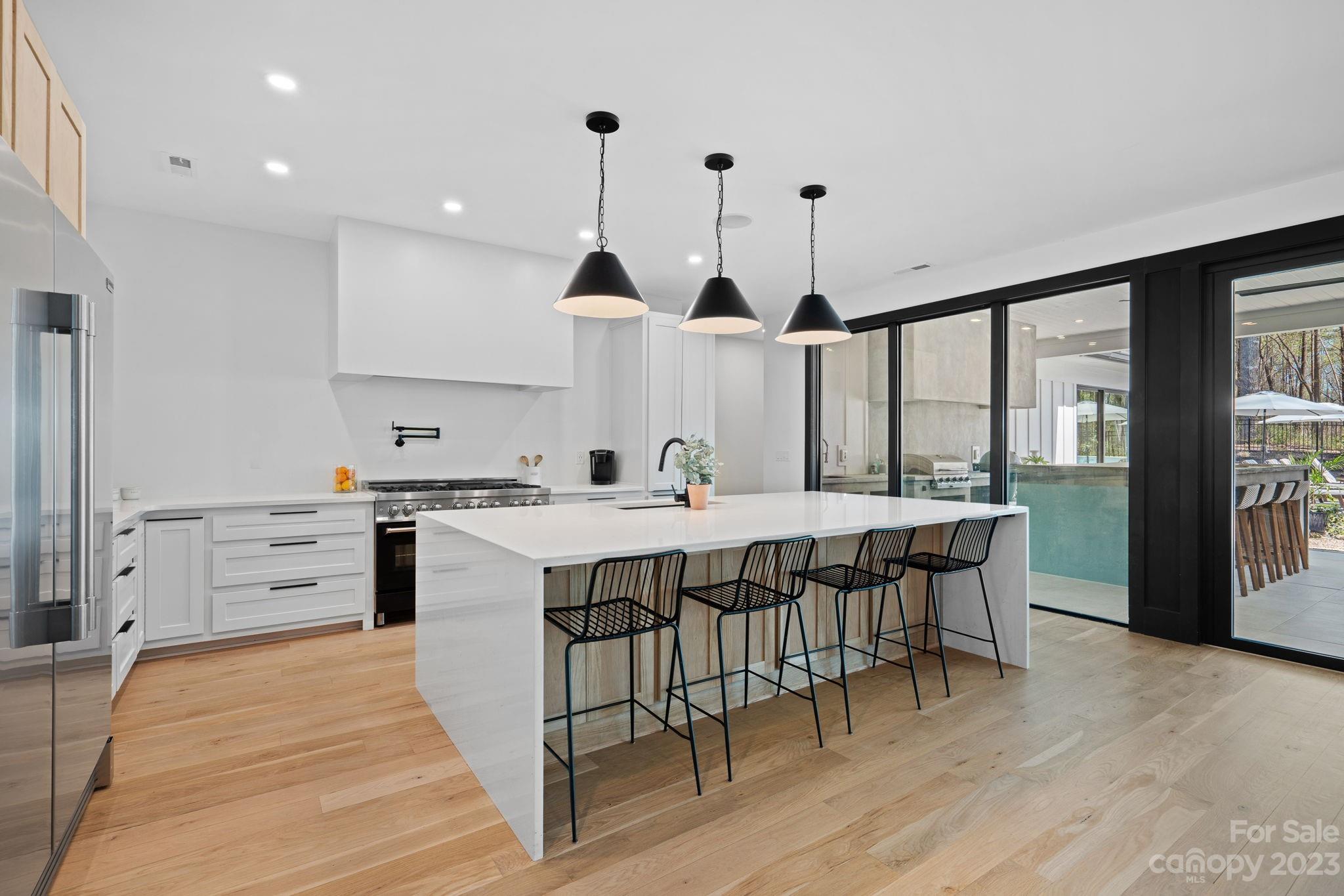 9622 Beatties Ford Road Huntersville, NC 28078 - Photo 9 of 48 a kitchen island with stainless steel appliances kitchen island granite countertop a table chairs sink and wooden floor