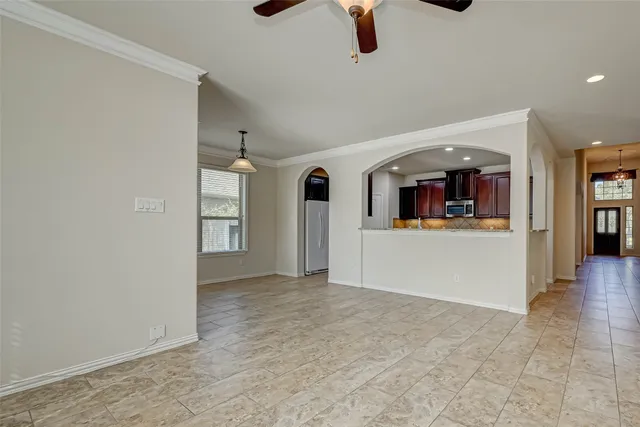 an empty room with windows and kitchen view