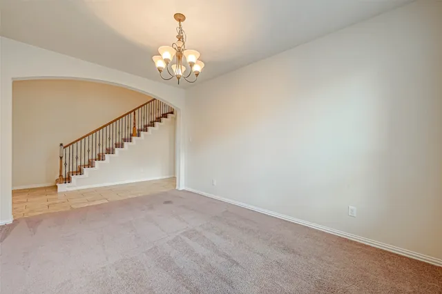 a view of an empty room with a chandelier fan