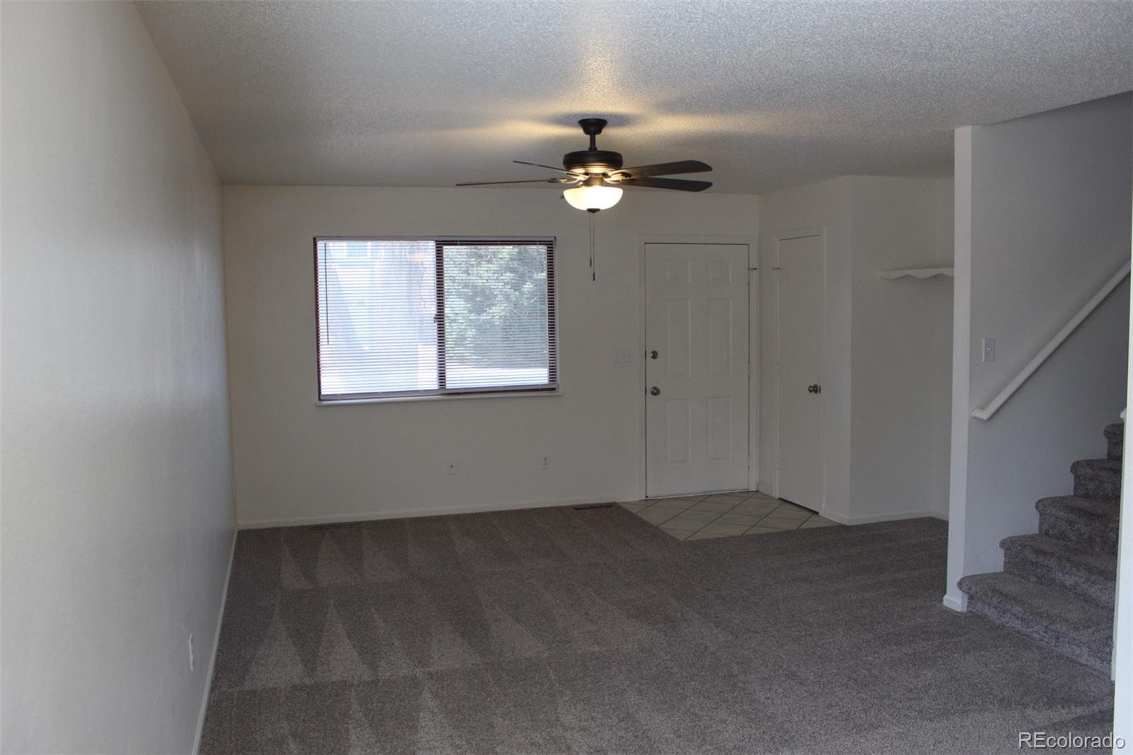 138 48th Avenue Greeley, CO 80634 - Photo 4 of 29 an empty room with a chandelier fan and windows