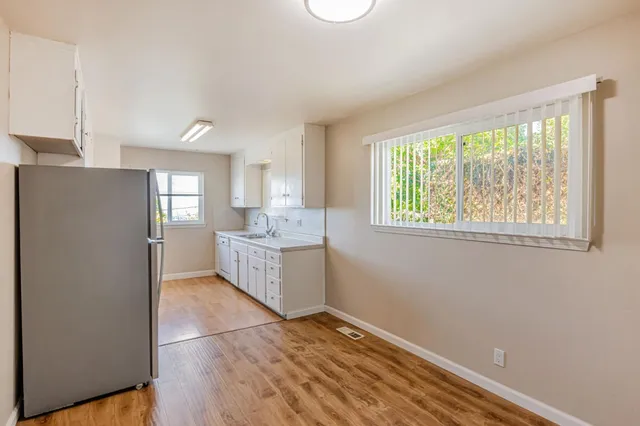 a view of a kitchen with refrigerator and wooden floor